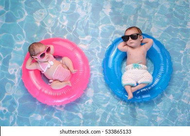生後 2 か月の双子の赤ちゃんの妹と弟が、小さな膨らませるピンクとブルーの浮き輪で寝ています。かぎ針編みの水着とサングラスを着用しています。