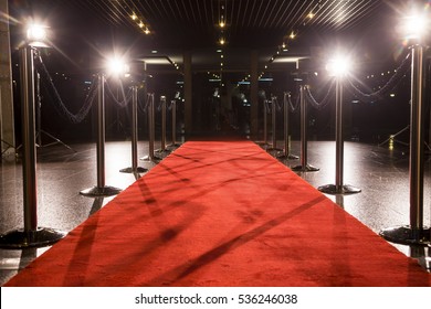 Larga alfombra roja entre barreras de cuerda en la entrada.