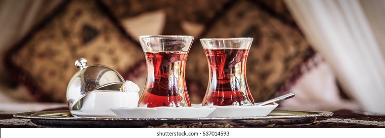 Hai tách trà kiểu Thổ Nhĩ Kỳ và niềm vui kiểu Thổ Nhĩ Kỳ với chiếc giường có màn trang trí kiểu phương Đông ở hậu cảnh. Khái niệm lãng mạn. Nền lễ tình nhân. Bầu không khí đêm Ả Rập. Ngang, định dạng biểu ngữ, xem trước, tông màu