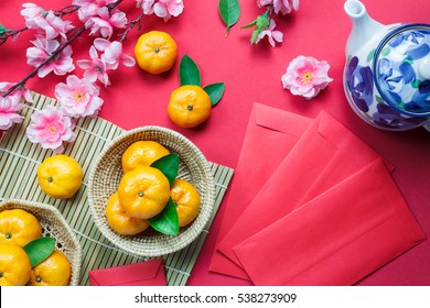 Phụ kiện nhìn từ trên xuống Trang trí lễ hội năm mới của Trung Quốc. cam, lá, giỏ gỗ, bao lì xì, hoa mận, ấm trà trên nền đỏ.