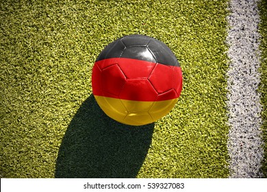 football ball with the national flag of germany lies on the green field near the white line