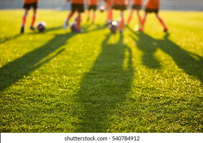 Campo de fútbol borroso en la escuela. Jóvenes futbolistas entrenando en campo. Fondo de hierba del estadio de fútbol