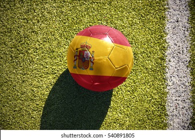 football ball with the national flag of spain lies on the green field near the white line