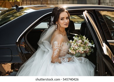la cabeza de joyería de la novia de cabello oscuro se sienta en un camión negro el día de su boda con un ramo. Retrato de la novia. vestido de encaje blanco esponjoso