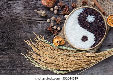 Yin Yang Zeichen mit schwarzem Reis und weißem Jasminreis auf hölzernem Hintergrund. Konzept gesunde Ernährung, Bio-Lebensmittel