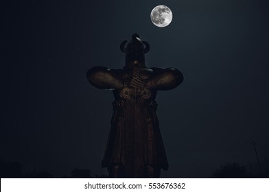 Silhouette vum Rittermonument mat Schwäert an der Nuecht a grousse helle Mound um Himmel, keltescht Landschaft
