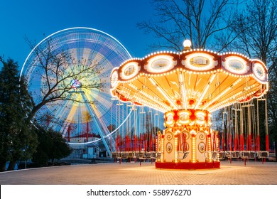 Roterende verlichte attractie reuzenrad en carrousel Merry-go-round op zomeravond In het stadspretpark.