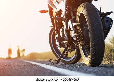 道路右側に駐輪するバイクと夕日、ピント合わせの背景を選択。