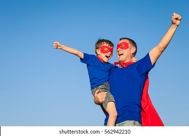 日中は父と息子がスーパーヒーローを演じている。屋外で楽しんでいる人々。フレンドリーな家族の概念。