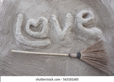 Carta de amor y escoba de bruja sobre arena