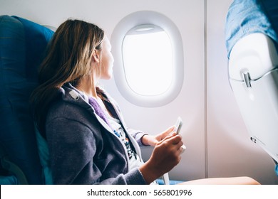 10 years old girl sitting inside airplane and looking at window