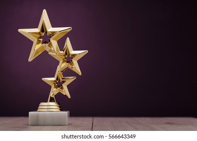紫色の背景にコピー スペースのある台座に立っている大会またはチャンピオンシップの 1 位に授与される 3 つの星を持つ金賞受賞者賞