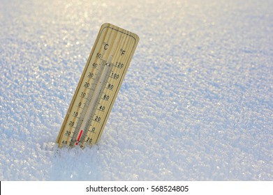 Kviksølv-trætermometer, der sidder fast på sne, viser meget lave temperaturer. Temperaturer i Celsius og Fahrenheit grader. Koldt vintervejr. Tyve grader under nul om dagen.