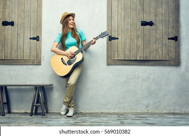 アコースティック ギターを弾く若い女性。全身肖像画。