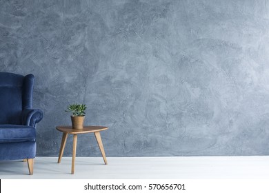 Interieur mit grauem, wandblauem Sessel und Beistelltisch aus Holz