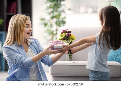 Kleines Mädchen, das ihrer Mutter zu Hause ein Geschenk gibt. Muttertagskonzept