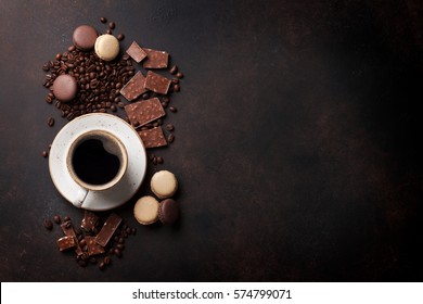 Coffee cup, beans, chocolate and macaroons on old kitchen table. Top view with copyspace for your text