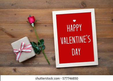 Tarjeta de feliz día de san valentín, caja de regalo y rosa roja sobre fondo de madera, pancarta