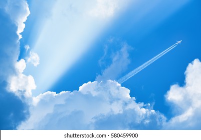 雲と太陽の光の間で青い空を飛んでいる飛行機