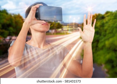 街の通りの光の道に対して仮想ビデオ眼鏡をかけている若い女性