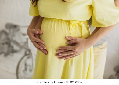 Bijgesneden afbeelding van mooie zwangere vrouw en haar knappe echtgenoot die de buik knuffelen