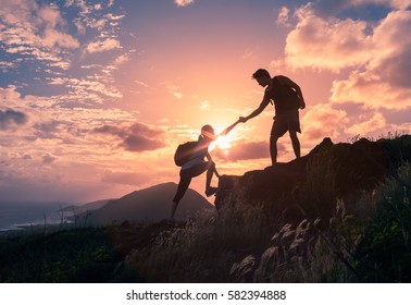 Mensen helpen elkaar bij zonsopgang een berg op. Een helpende hand bieden, en een actief fit levensstijlconcept.