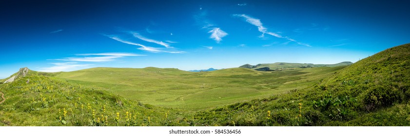 Genähtes Panorama der üppigen grünen Hügel in der Auvergne-Landschaft in Frankreich unter einem sonnigen blauen Himmel in einem Reise- und Urlaubskonzept