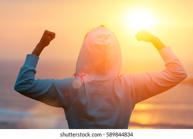 太陽に向かってワークアウトの目標を祝う強い意欲的な女性の背面図。朝の健康トレーニング成功。