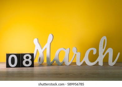 Frohe Internationale Frauentage. 8. März. Tag 8 des Monats, täglicher Holzkalender auf dem Tisch mit gelbem Hintergrund. Leerer Platz für Text.