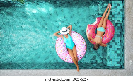 Hai người (mẹ và con) thư giãn trên bánh donut lilo trong hồ bơi tại biệt thự riêng. Kỳ nghỉ hè bình dị. Nhìn từ trên cao xuống.