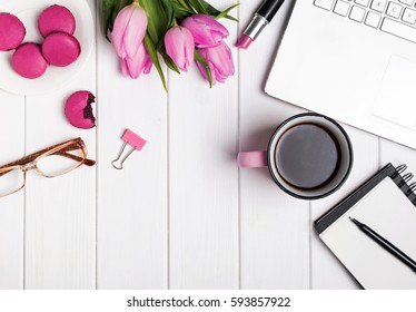 Máy tính để bàn của người phụ nữ với máy tính xách tay, notepad, kính, cà phê và hoa tulip. nhìn từ trên xuống