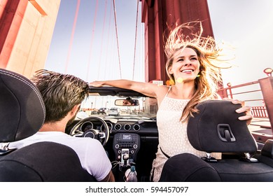 Paar geliefden rijden op een cabriolet - pasgetrouwd stel op een romantische date, vrouw met uitgestrekte armen op Golden Gate Bridge