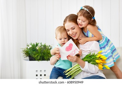 Selamat Hari Ibu! Anak-anak mengucapkan selamat kepada ibu dan memberinya kartu pos dan bunga tulip