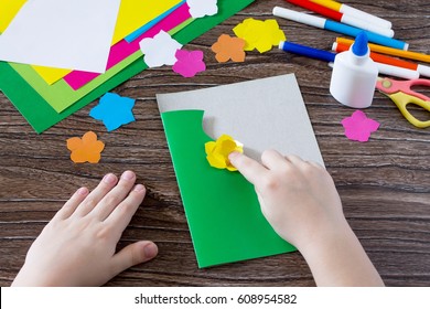 Het kind knipt de details uit het papier. Wenskaart met bloemen op Moederdag. Kunstproject voor kinderen, knutselen voor kinderen. Handgemaakt. Ambacht voor kinderen.
