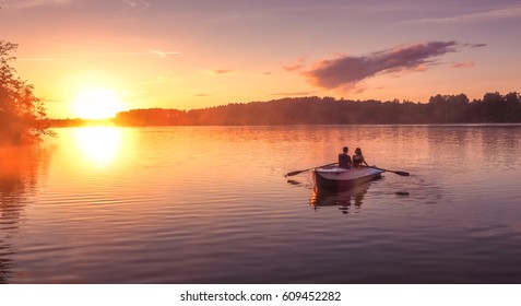 A beautiful golden sunset on the river. Lovers ride in a boat on a lake during a beautiful sunset. Happy couple woman and man together relaxing on the water. The beautiful nature around.