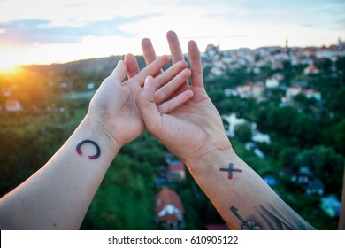 Small couple tattoo on hands wrists above the town while sundown. Couple holding hands to each other. Romantic photography,