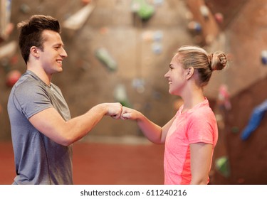fitness, extreme sport, bouldering, people and healthy lifestyle concept - man and woman exercising at indoor climbing gym making fist bump gesture