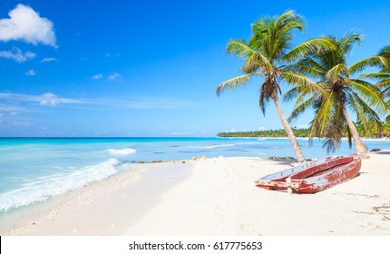 ヤシの木と古い赤い遊覧船が白い砂浜に立っています。カリブ海、ドミニカ共和国、サオナ島の海岸、人気の観光地