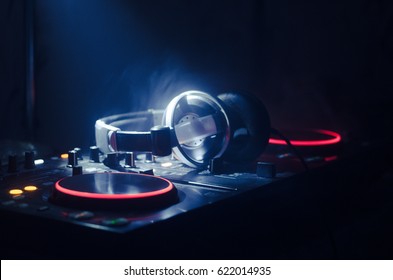DJ draaien, mixen en krabben in een nachtclub, handen van dj tweaken verschillende trackcontroles op dj's deck, stroboscooplichten en mist, selectieve focus, close-up. Dj Muziek clubleven concept