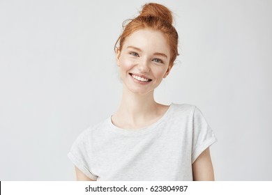 カメラを見て笑っているそばかすのある幸せな生姜の女の子のヘッド ショットの肖像画。白色の背景。