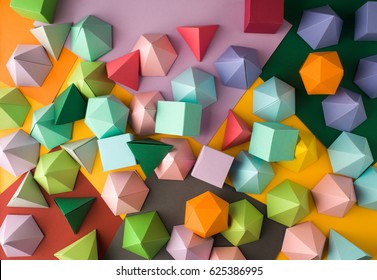 Kleurrijke abstracte geometrische achtergrond met driedimensionale stevige cijfers. Piramide dodecaëder prisma rechthoekige kubus gerangschikt op gekleurd papier.