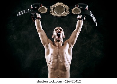 Boxeador con cinturón de campeón celebrando una victoria impecable aislado en fondo negro con espacio de copia.