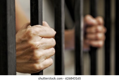 黒い金属棒を持つ囚人の手、解放を待っている刑務所に閉じ込められた犯罪者