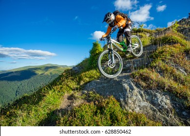 Un hombre está montando en bicicleta, en el fondo de las montañas y el cielo azul. Hermoso día de verano. Carrera de bicicleta de montaña