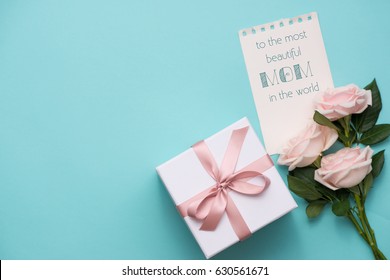 Konzept zum Muttertag. Strauß rosa Rosen mit Geschenkbox und Lippenstift. Leere Papiernotiz für Kopienraum.
