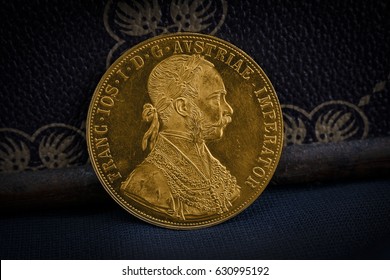 Close-up view of Austria-Hungary thaler, avers of golden coin-ducat from 1915 with Kaiser Franz Joseph I, leaning on treasure chest with dark environment