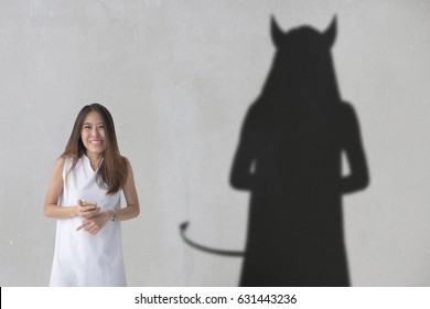 Aziatische vrouw ziet eruit alsof ze een grap aan het uitzetten is terwijl ze een duivelse schaduw heeft.