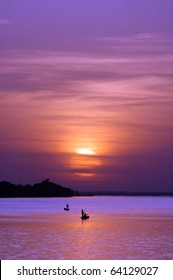 後ろに夕日が沈む川のアフリカの漁師