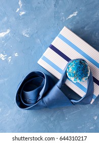 Tarjeta del día del padre con caja de regalo y pastel de taza, corbata sobre fondo azul.