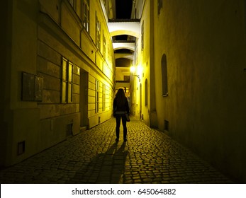 Girl walking empty dark alley during night.